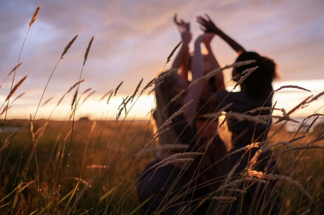 Women with hands raised together in a field